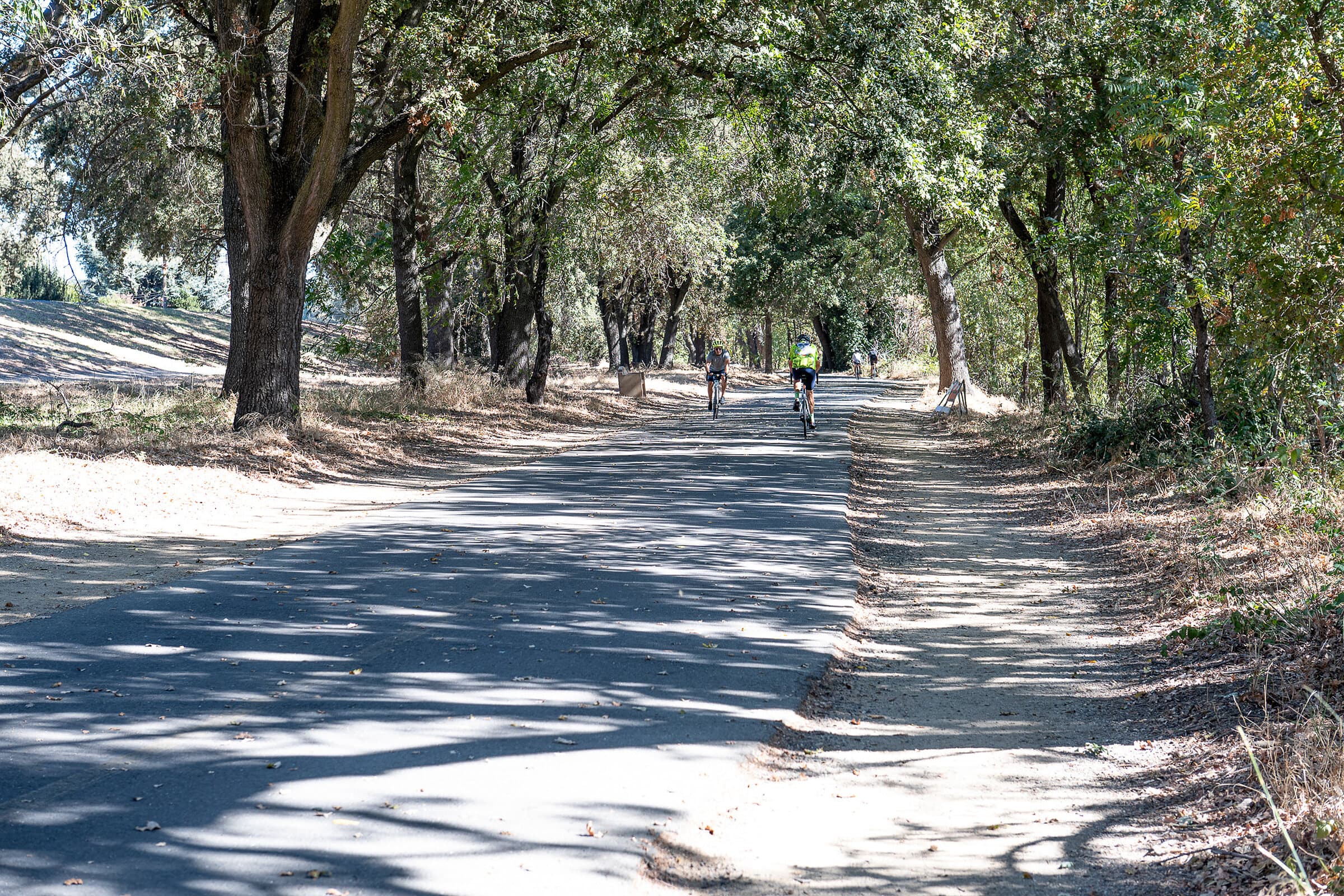 Cyclists on the oak-shaded American River Parkway trail at the Kadema access near Sierra Oaks