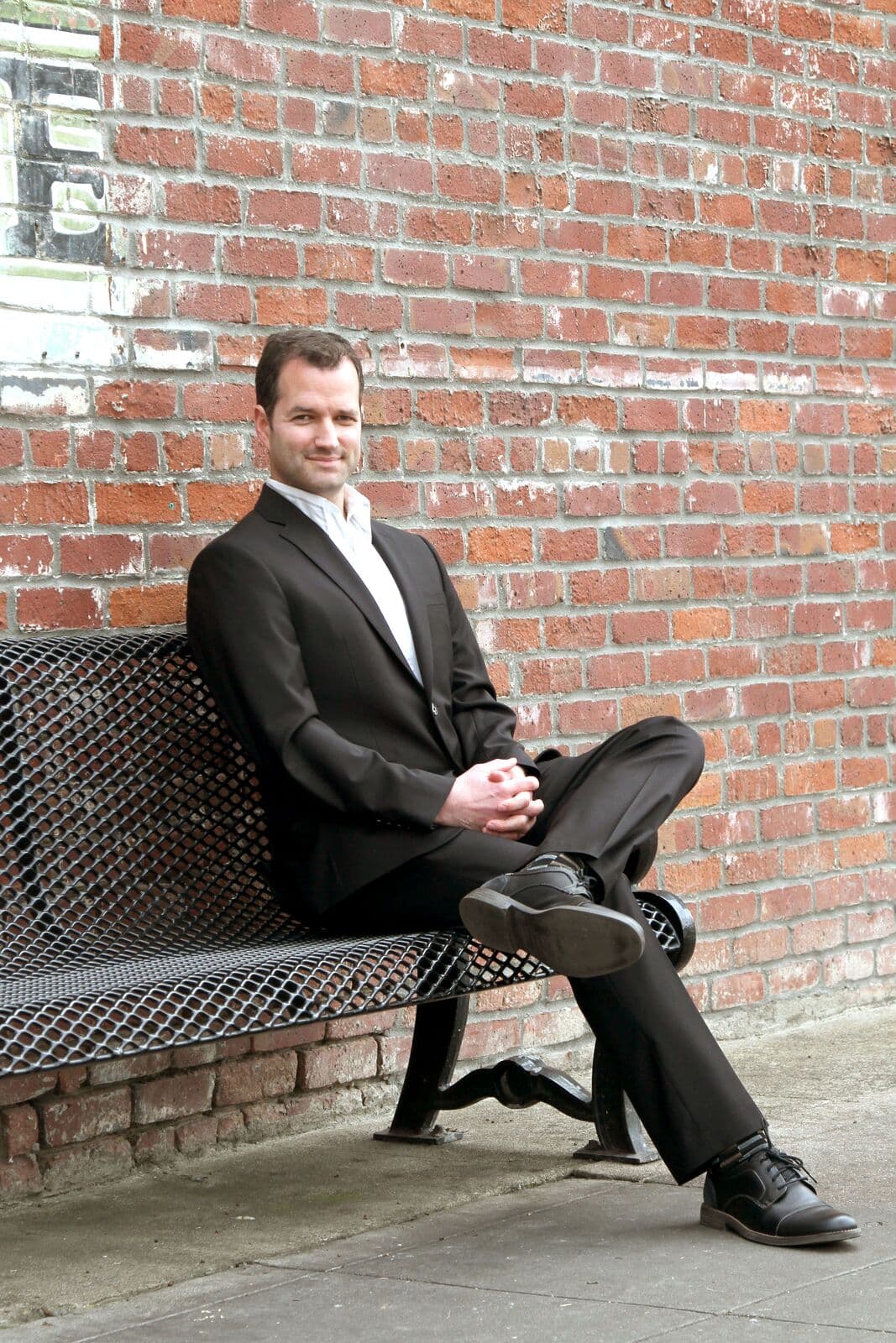 Joseph Olson seated against a brick wall