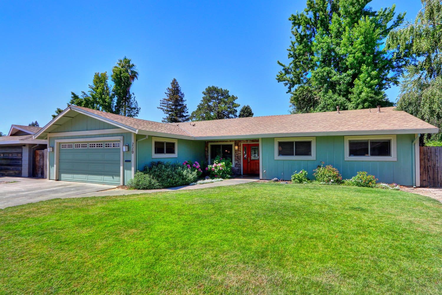 A single-story ranch home with a green front lawn