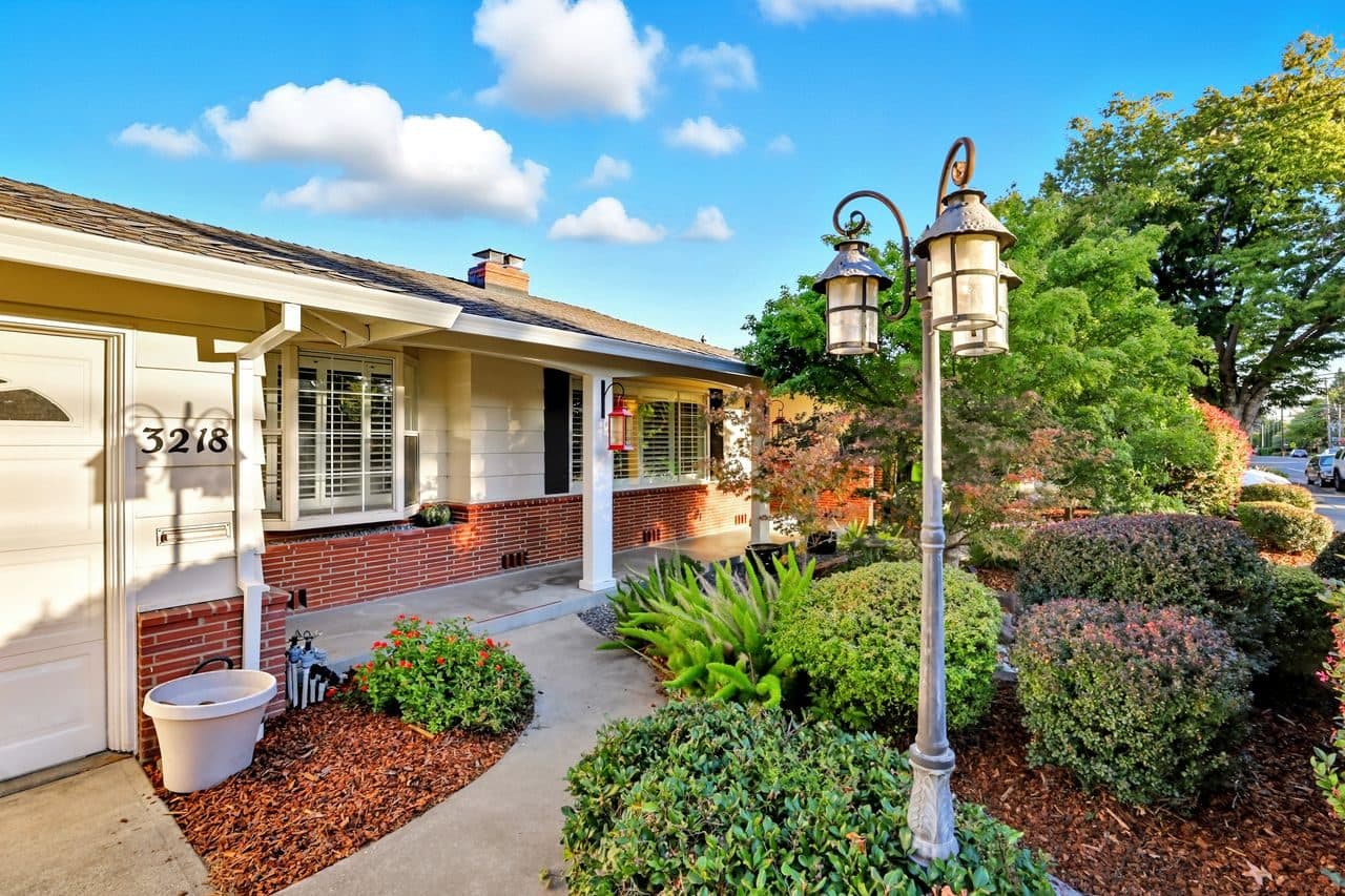 A brick-front home with a garden and lamppost